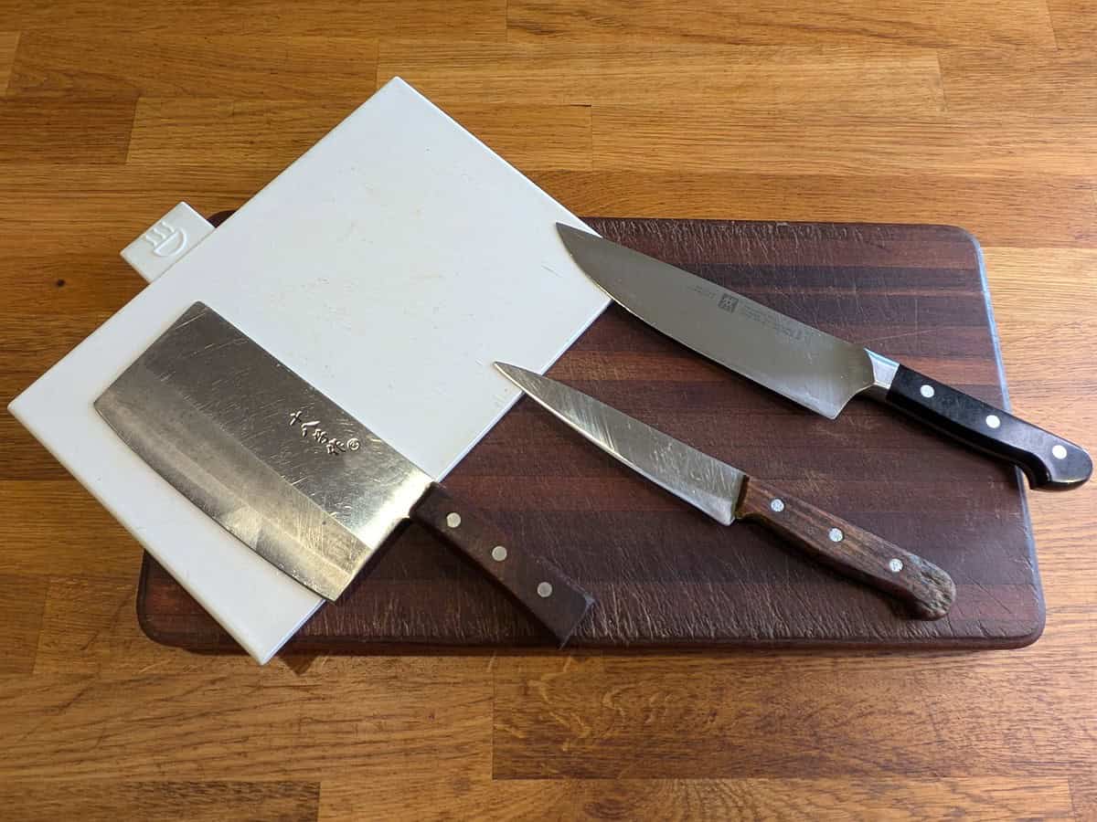 A selection of knives and a chopping board used in preparing Thai dishes