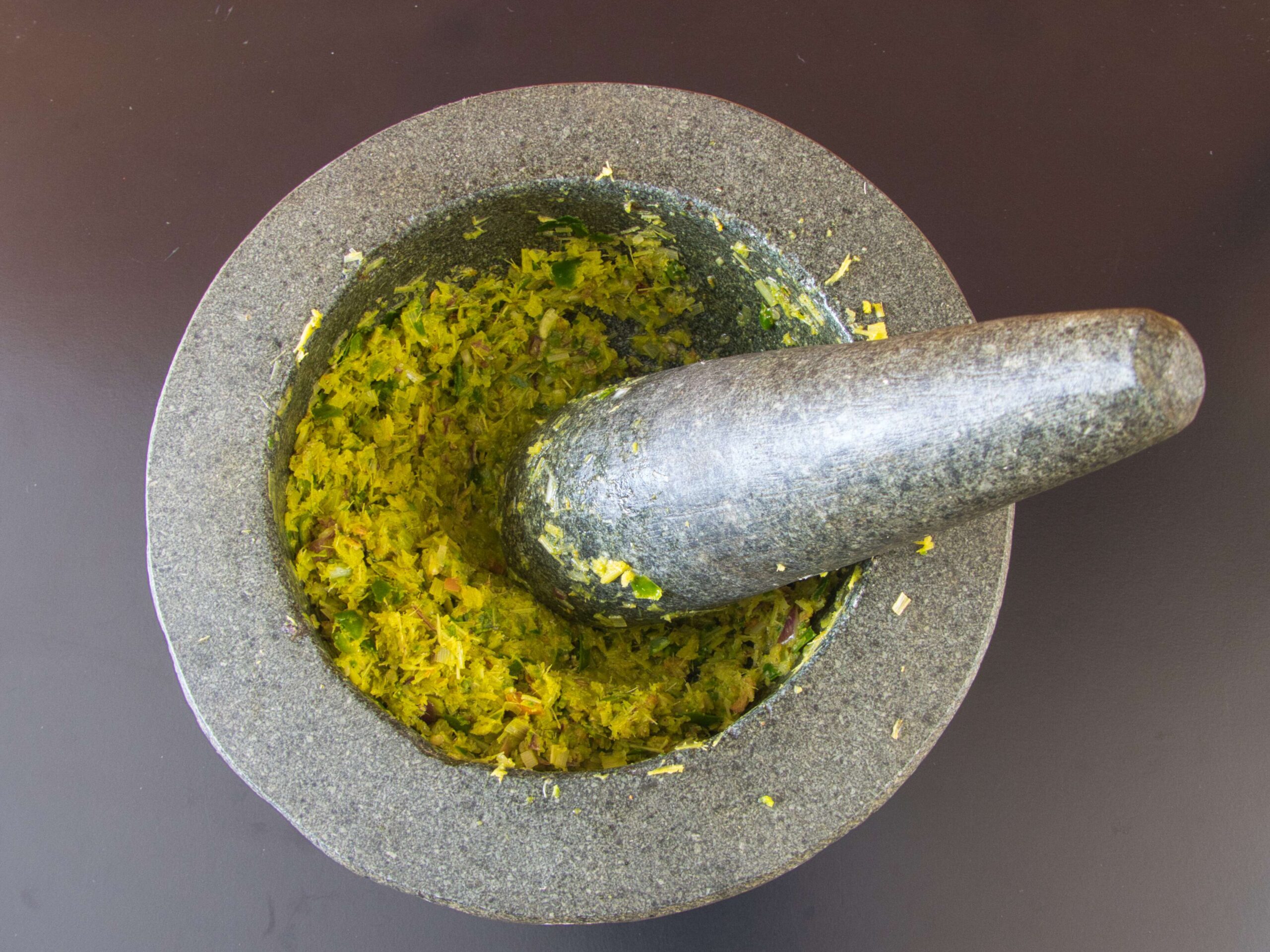 "Grinding fresh ingredients in a traditional mortar and pestle to create aromatic Thai green curry paste