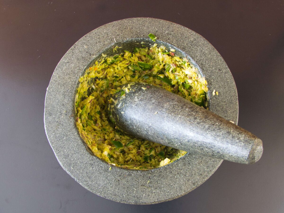 "Grinding fresh ingredients in a traditional mortar and pestle to create aromatic Thai green curry paste