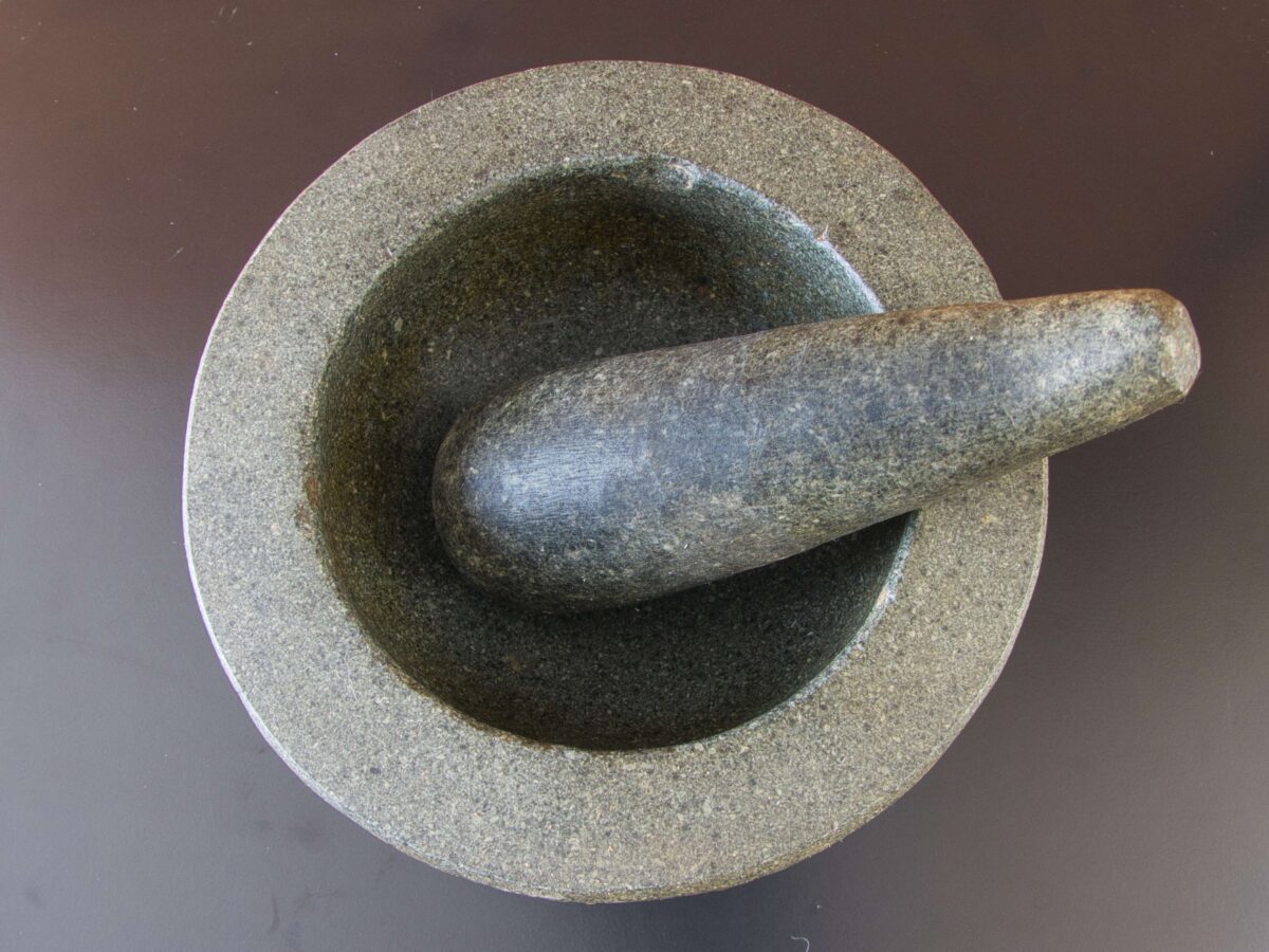 A traditional stone mortar and pestle used for grinding fresh ingredients into Thai green curry paste.