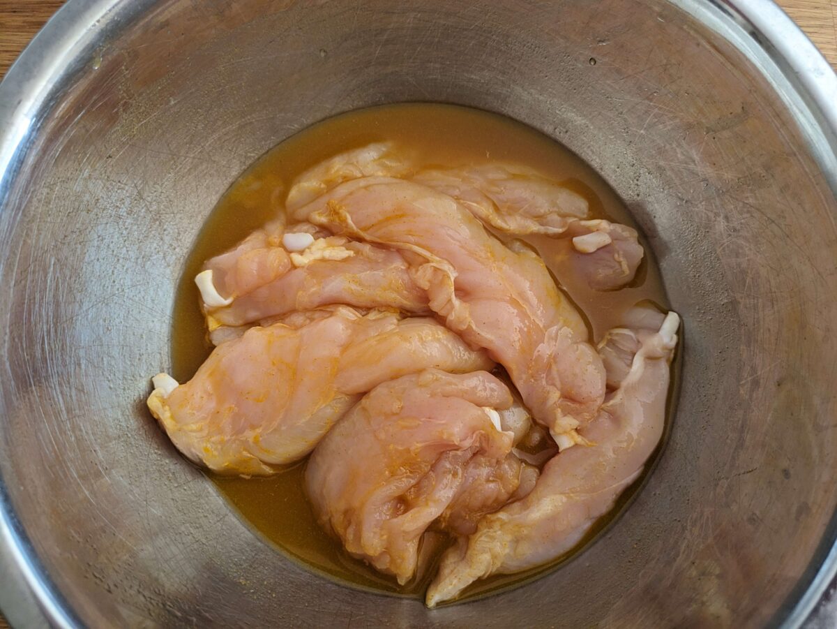"Chicken tenderloins marinating in Thai satay marinade for chicken satay"