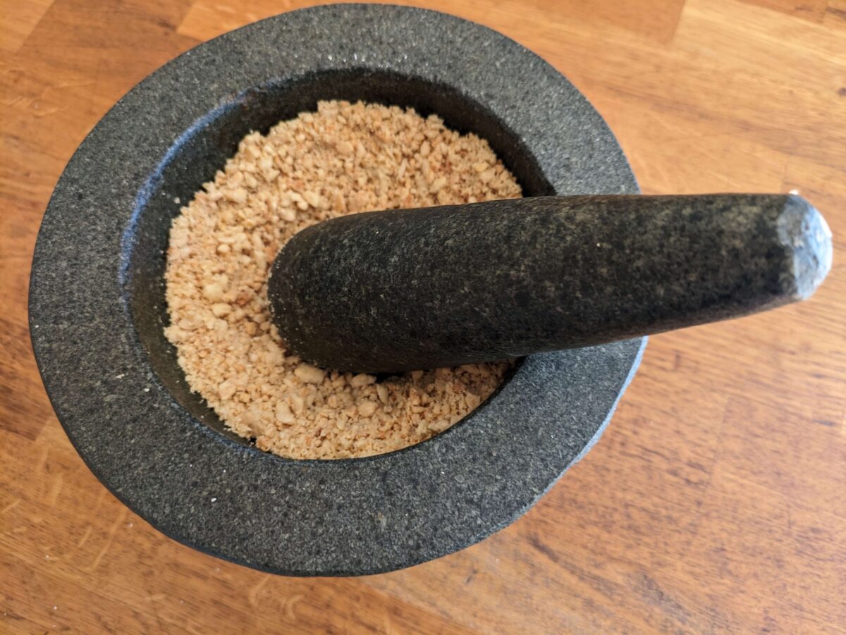 Fresh peanuts being ground in a mortar to make authentic Thai peanut sauce"