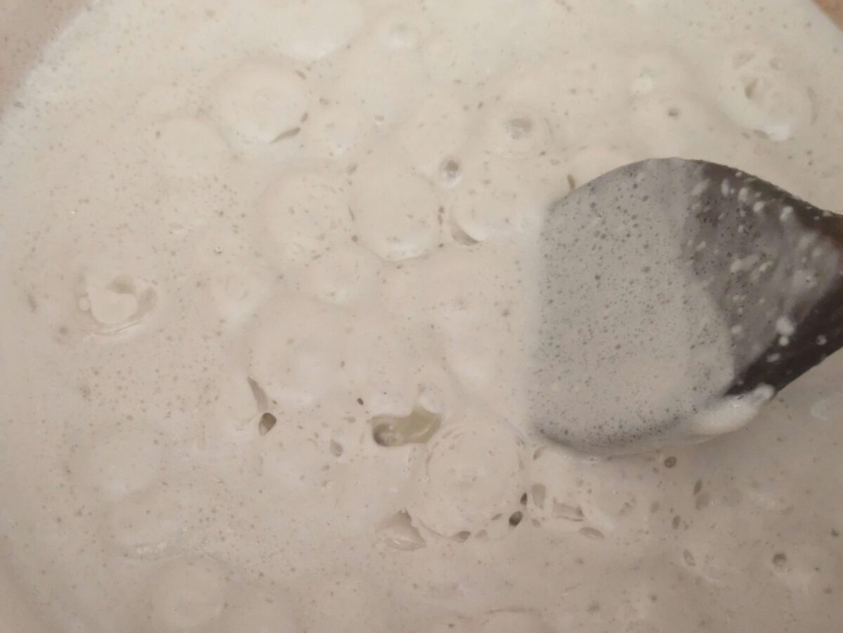 “Coconut cream gently simmering and reducing to create a rich, creamy base to fry the red curry paste when making Thai peanut sauce.”