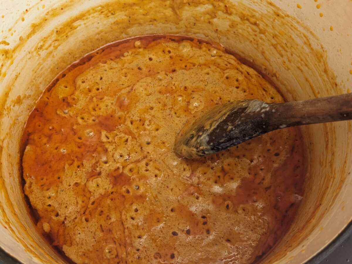 Red curry paste sizzling in coconut cream — the foundation of rich, aromatic Thai peanut sauce.”