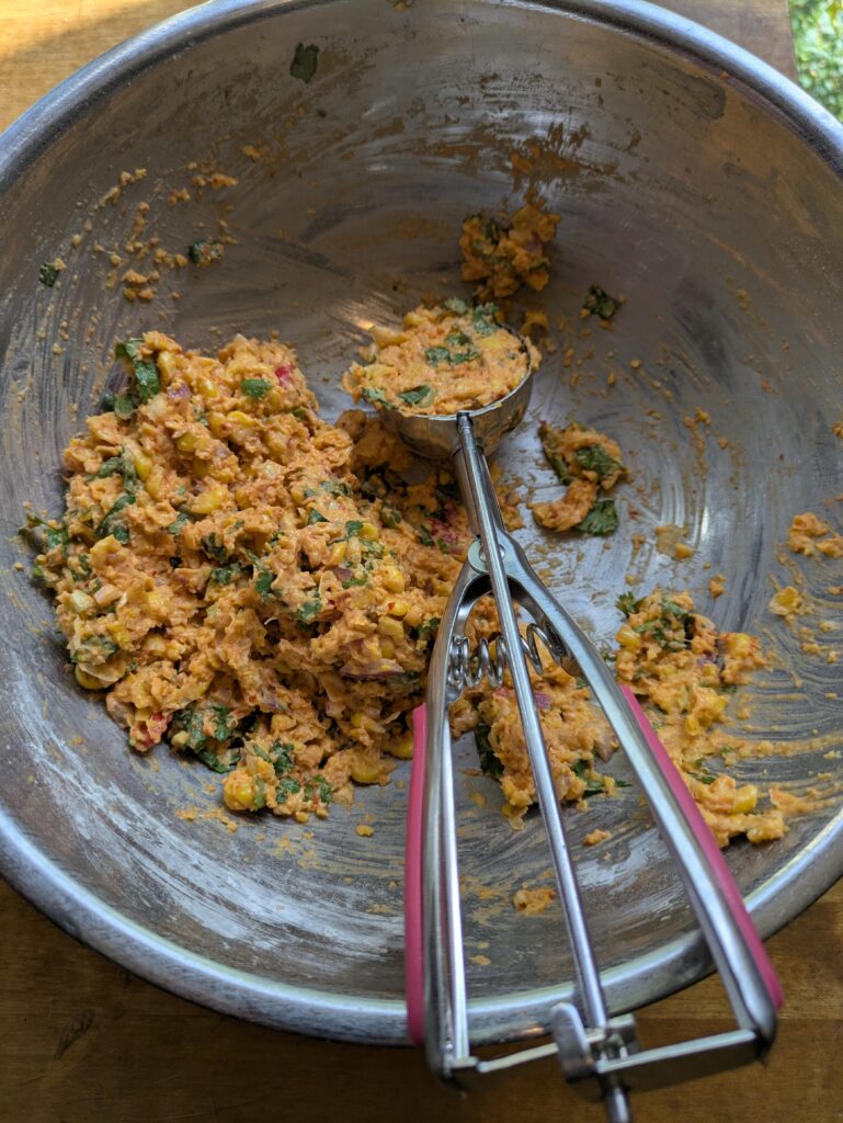 Portioning corn fritter mixture using an ice cream scoop.”