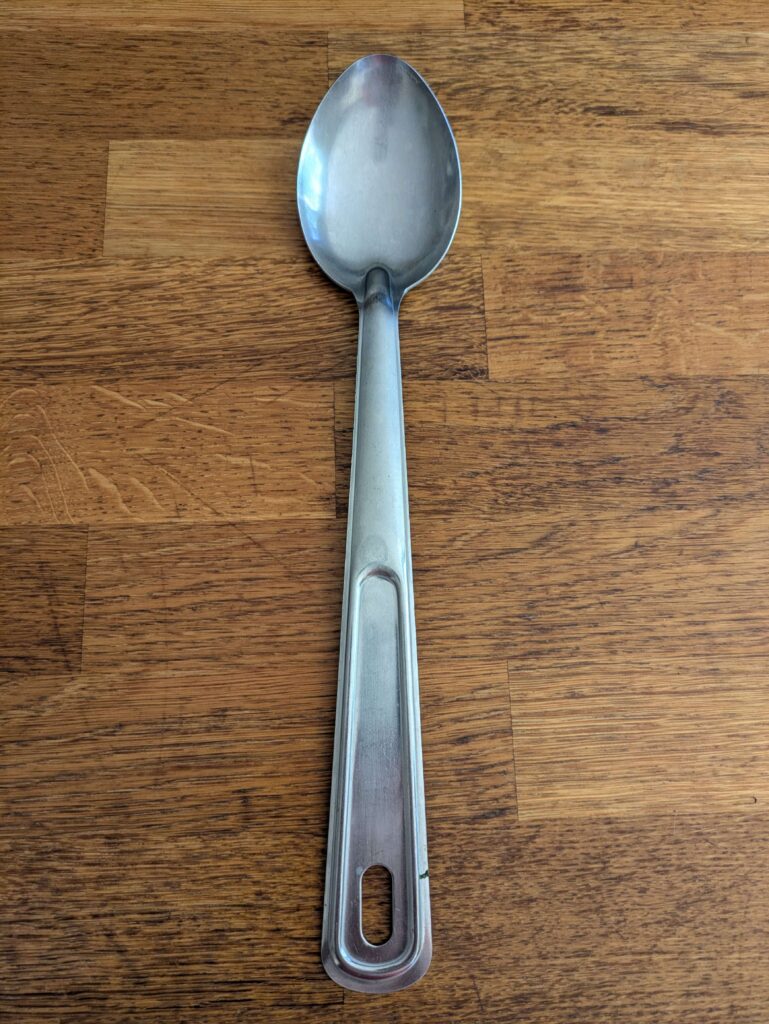 Metal spoon on a kitchen bench for mixing chicken laab