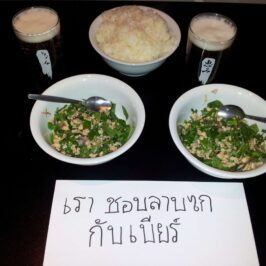 A staff meal favourite: Thai chicken laab served with cold beer and a handwritten sign reading “We love laab gai with beer,” capturing the simple pleasures of life in the kitchen after service.