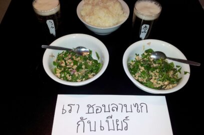 A staff meal favourite: Thai chicken laab served with cold beer and a handwritten sign reading “We love laab gai with beer,” capturing the simple pleasures of life in the kitchen after service.