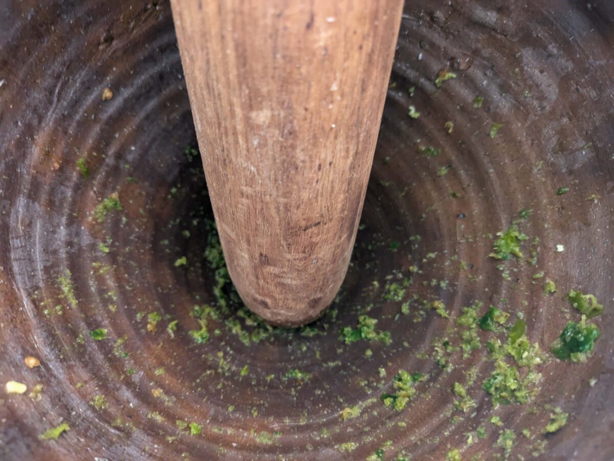 Ground green chillies and salt in a mortar for Thai chilli dressing
